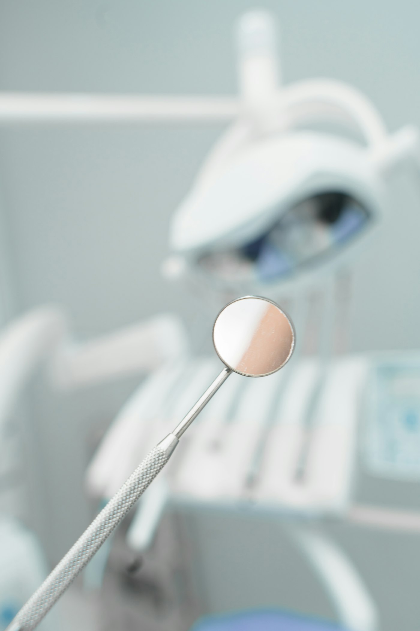 A dental mirror held up in front of a treatment chair