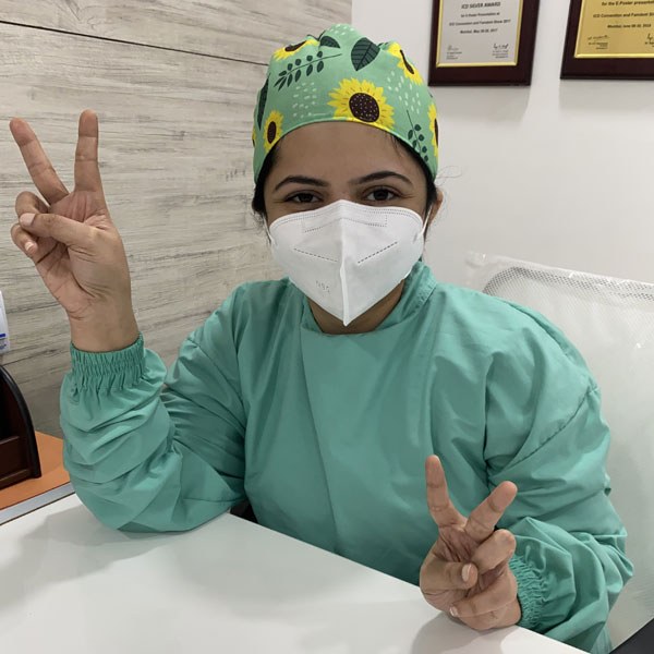 Dr. Shraddha Karkhanis in surgical scrubs at her clinic desk